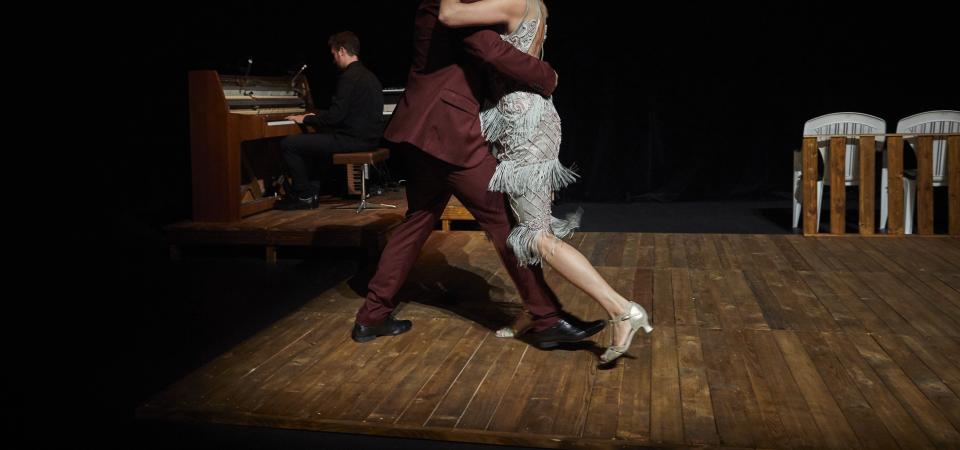 Ein Mann und eine Frau tanzen im halbdunkel Walzer, auf einem Braunen Holzboden